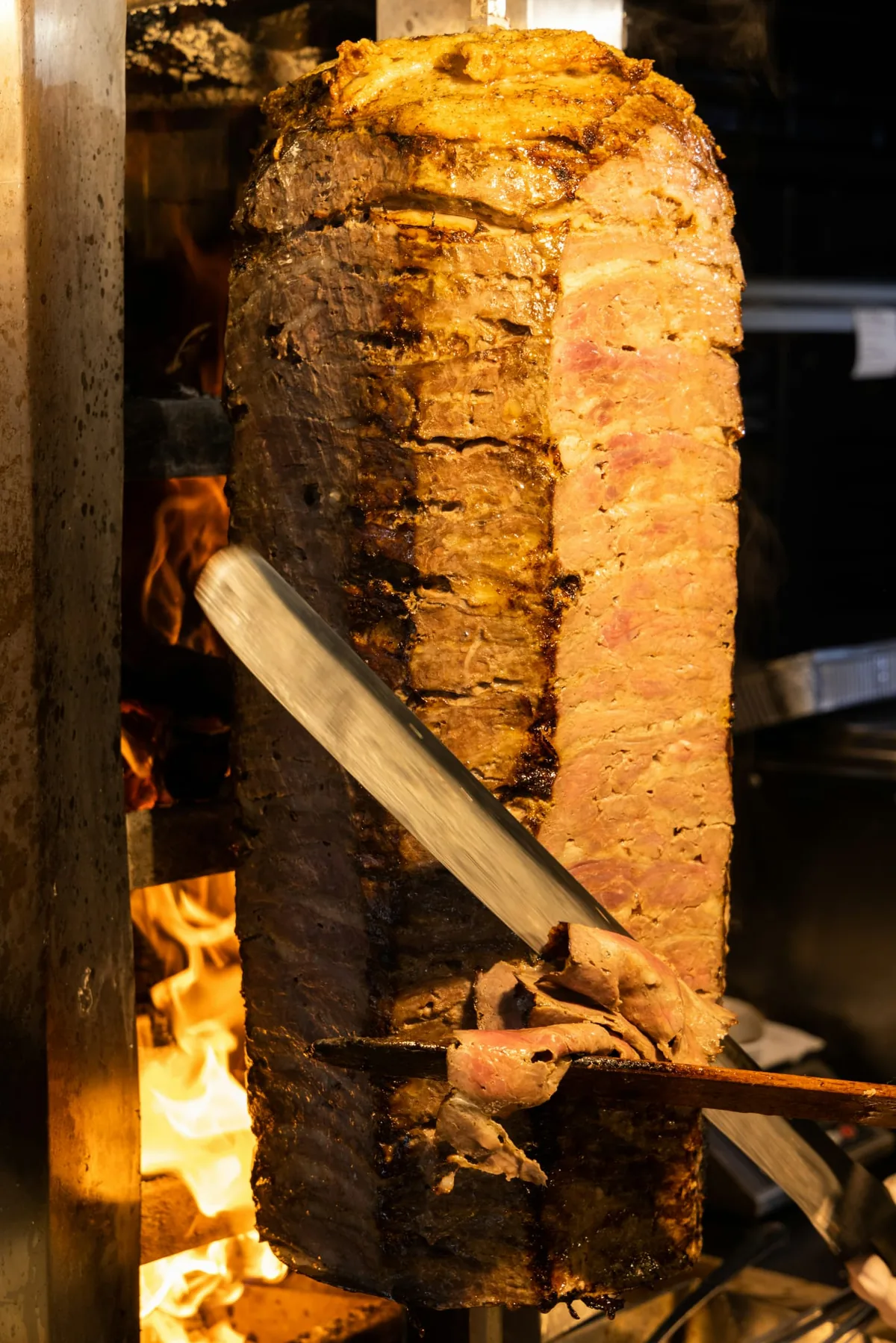 La broche de döner tranchée devant le feu de bois